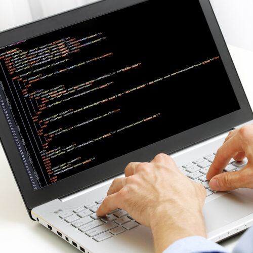 Hands typing code on a laptop keyboard