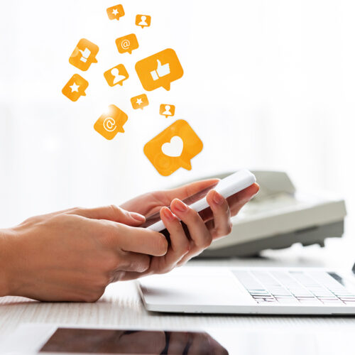 Hands holding a smartphone with social media icons representing social media management